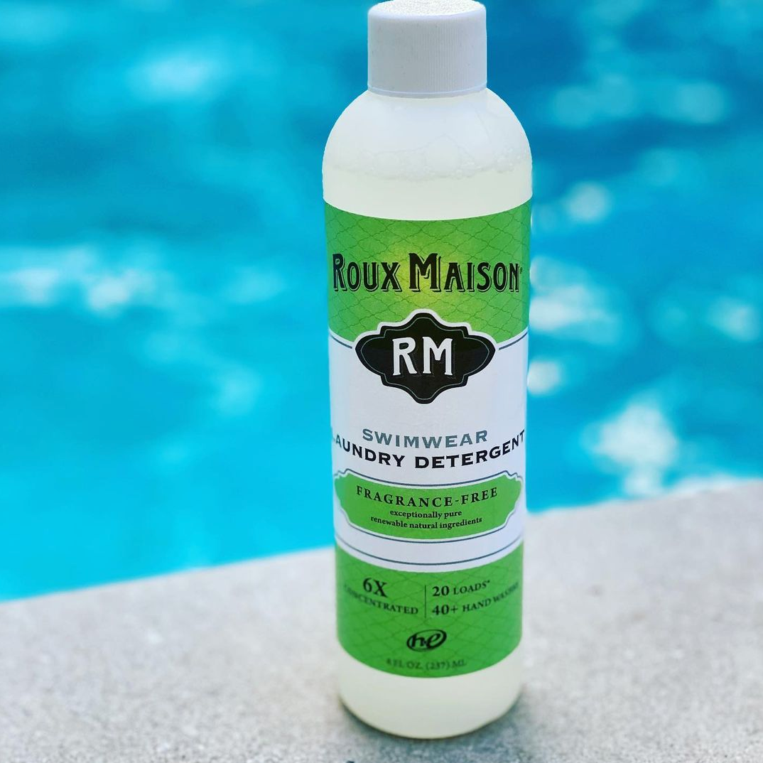 Roux Maison Swimwear Detergent 8 oz & 1oz with pink goggles next to a pool